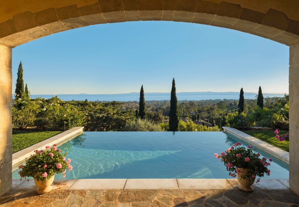 Infinity pool at 965 Brooktree Road framed by a stone arch, looking out to the Pacific and the Channel Islands